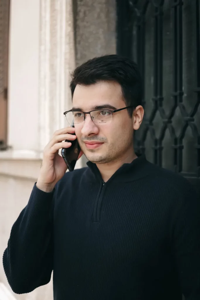 Muškarac sa dioptrijskim naočarima razgovara telefonom